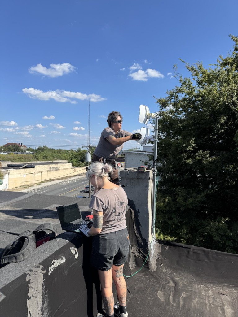 Philly Whisper technicians installing a wireless radio on a rooftop.