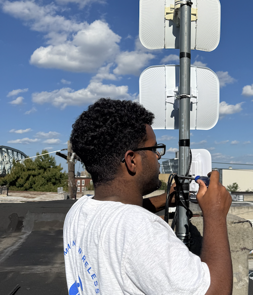 Apprentice Francisco Oquendo installing a wireless radio on a rooftop.